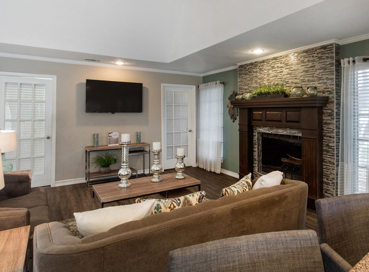 Clubhouse interior with  wall mounted television, fireplace, sofa, and a coffee table with decorations